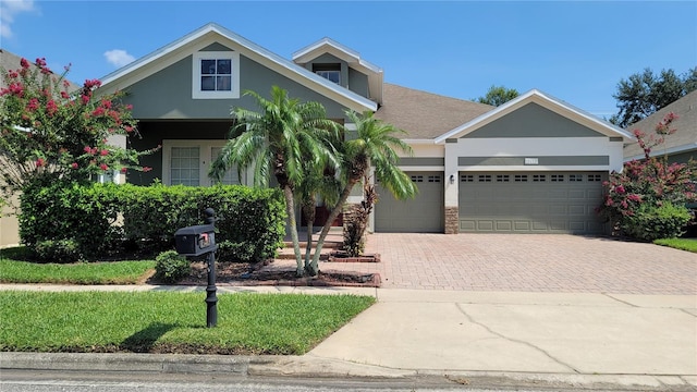 view of front of property with decorative driveway, an attached garage, and stucco siding