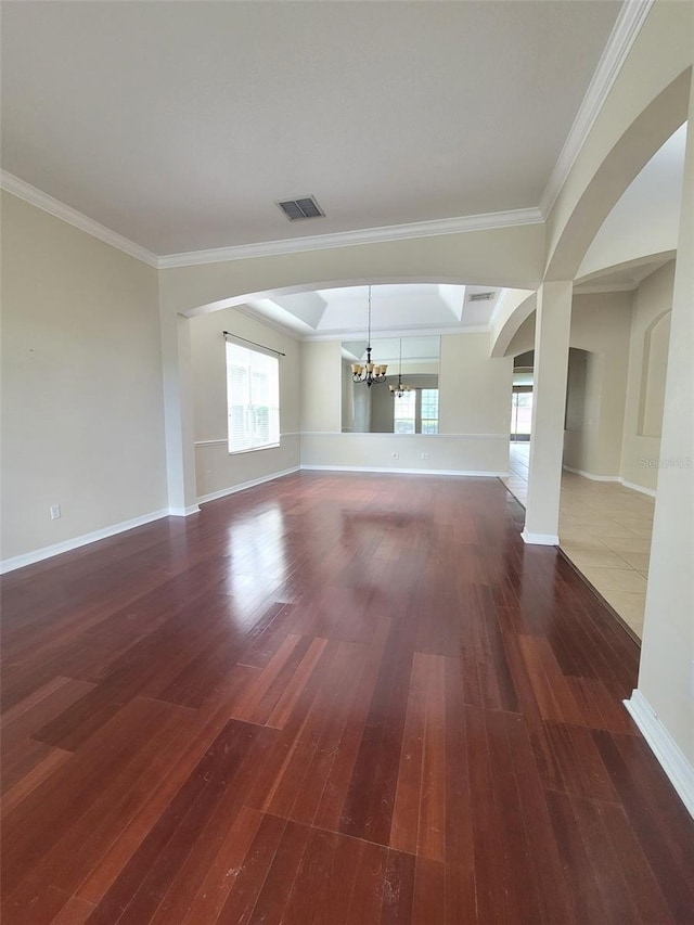 unfurnished living room with visible vents, baseboards, wood finished floors, an inviting chandelier, and crown molding