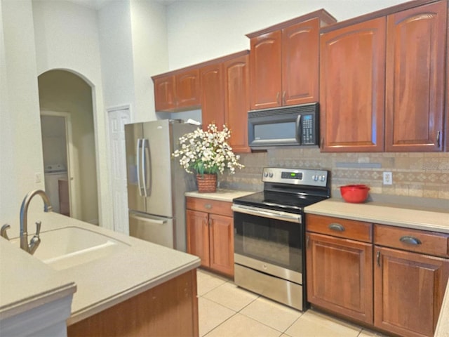 13413 Zori Ln, Windermere, FL 34786 - kitchen with appliances with stainless steel finishes, arched walkways, light countertops, light tile patterned floors, and tasteful backsplash