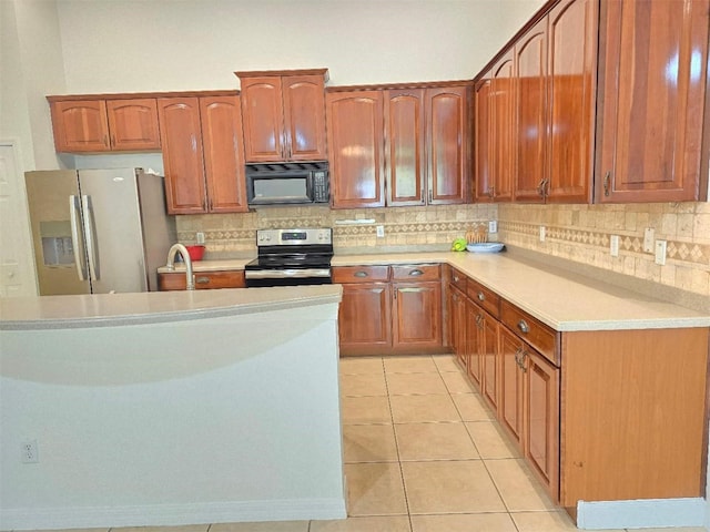 13413 Zori Ln, Windermere, FL 34786 - kitchen with range with electric stovetop, black microwave, stainless steel fridge, decorative backsplash, and light countertops
