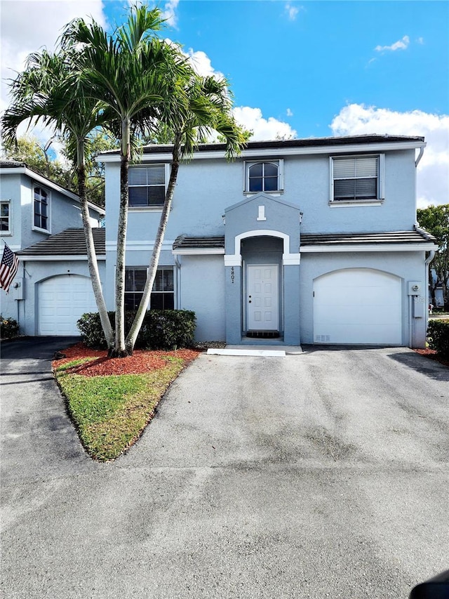 traditional-style home featuring aphalt driveway, an attached garage, and stucco siding