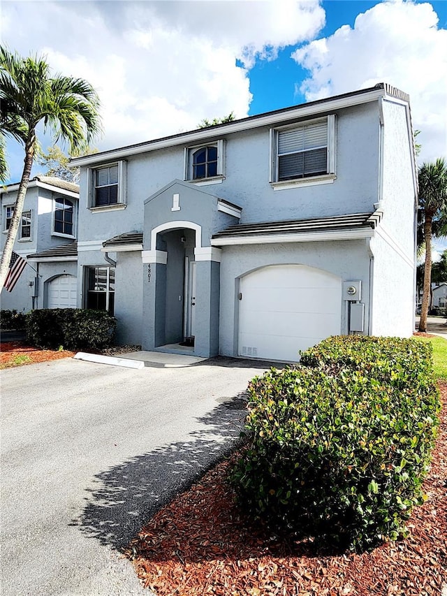 traditional-style house featuring an attached garage, aphalt driveway, and stucco siding