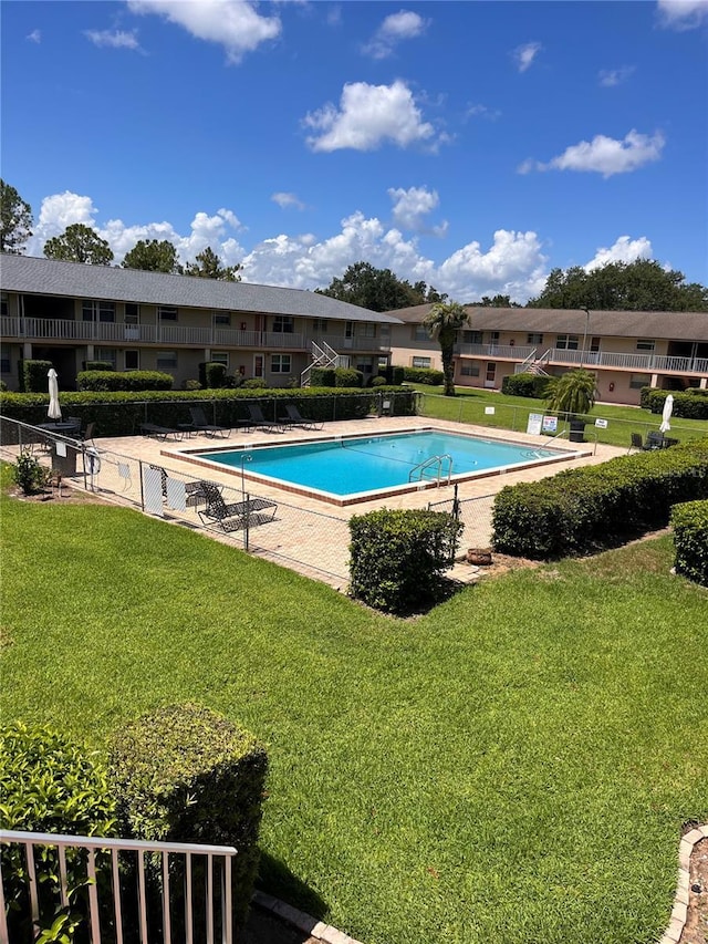 community pool with fence and a lawn