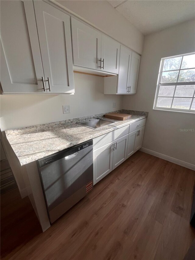 kitchen with dark wood finished floors, white cabinetry, light countertops, and stainless steel dishwasher