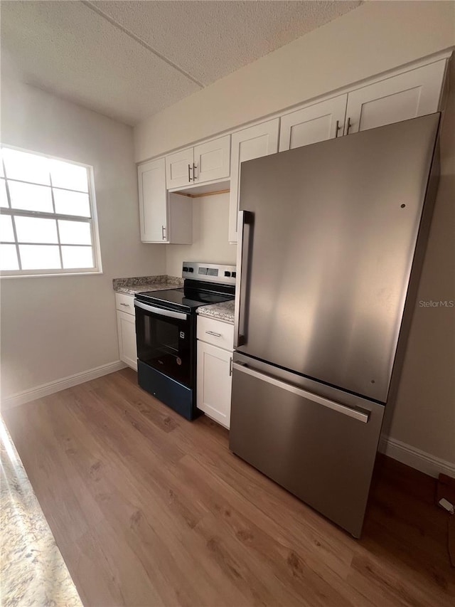 kitchen featuring range with electric cooktop, freestanding refrigerator, white cabinetry, and wood finished floors