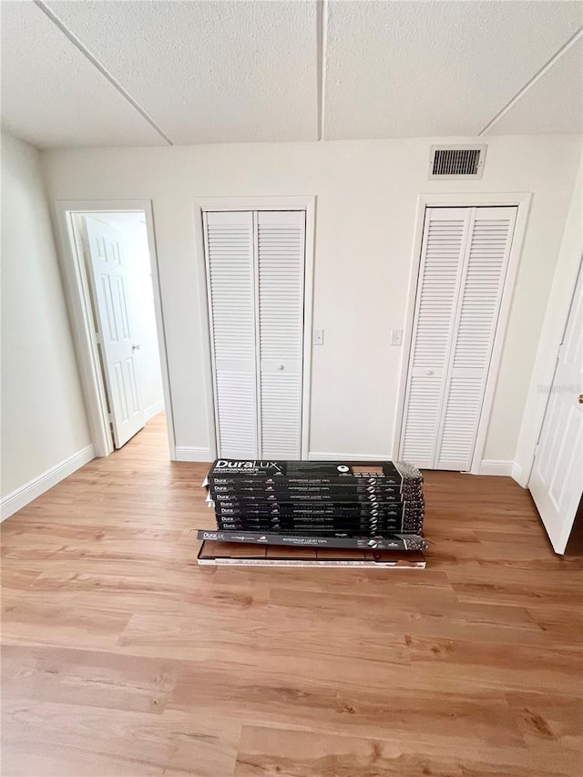 interior details featuring a textured ceiling, wood finished floors, visible vents, and baseboards