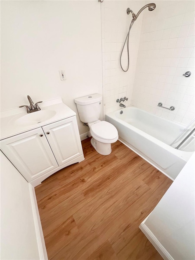 full bathroom featuring toilet, wood finished floors, vanity, baseboards, and  shower combination