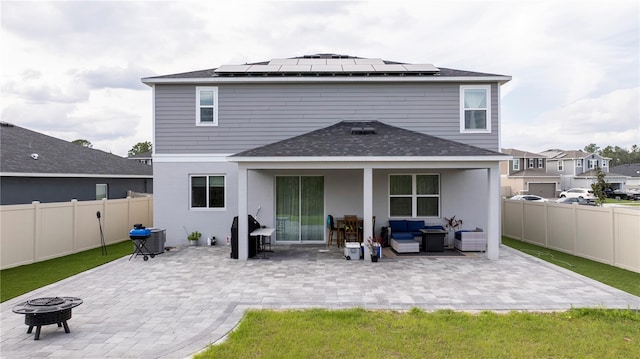 rear view of property with a patio, a fenced backyard, central AC, solar panels, and an outdoor living space with a fire pit