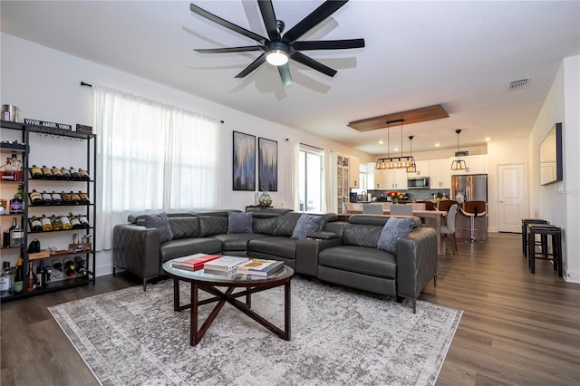 living area with dark wood-style floors, visible vents, and a ceiling fan