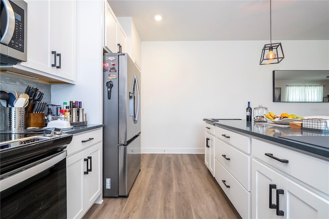 kitchen featuring light wood-type flooring, appliances with stainless steel finishes, dark countertops, and white cabinetry