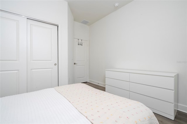 bedroom with dark wood-type flooring, a closet, visible vents, and baseboards