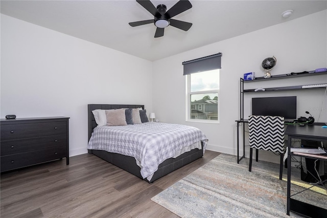 bedroom with ceiling fan, wood finished floors, and baseboards