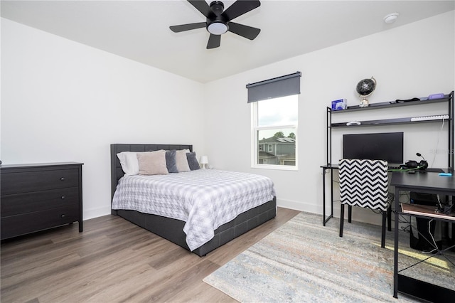 bedroom with ceiling fan, wood finished floors, and baseboards