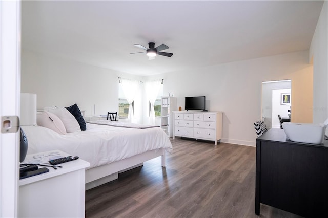 bedroom with ceiling fan, wood finished floors, and baseboards