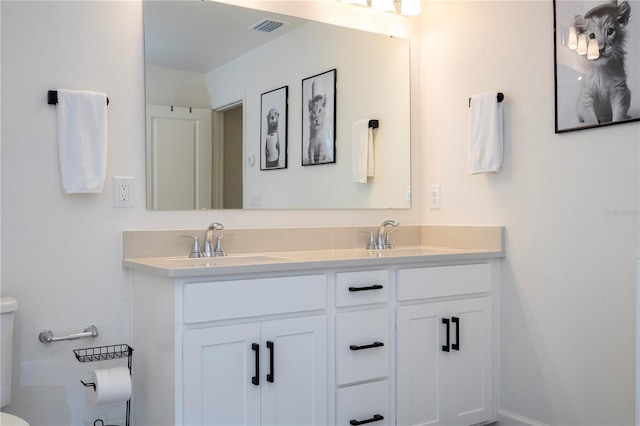 bathroom with visible vents, a sink, toilet, and double vanity