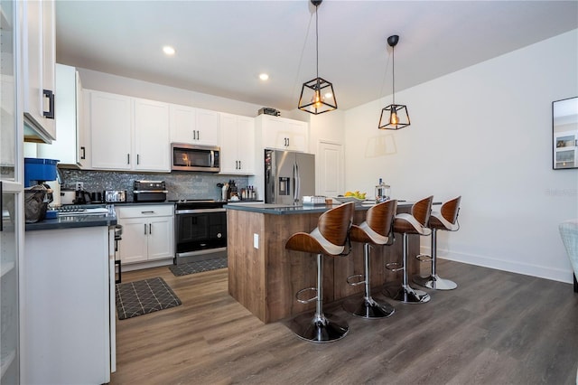 kitchen featuring appliances with stainless steel finishes, dark countertops, white cabinets, and tasteful backsplash