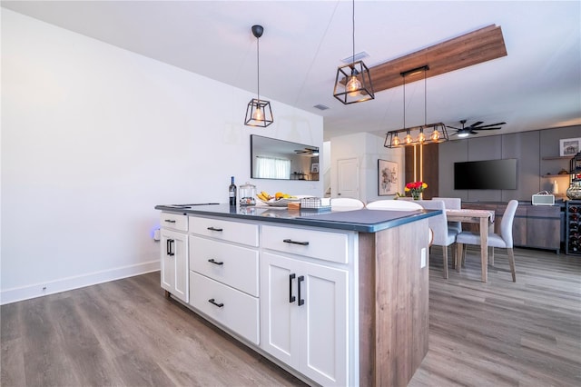 kitchen with dark countertops, a kitchen island, wood finished floors, and hanging light fixtures