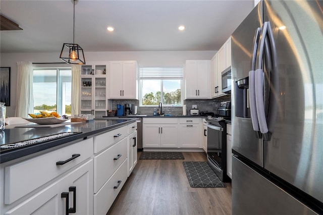 kitchen featuring appliances with stainless steel finishes, dark countertops, white cabinets, and tasteful backsplash