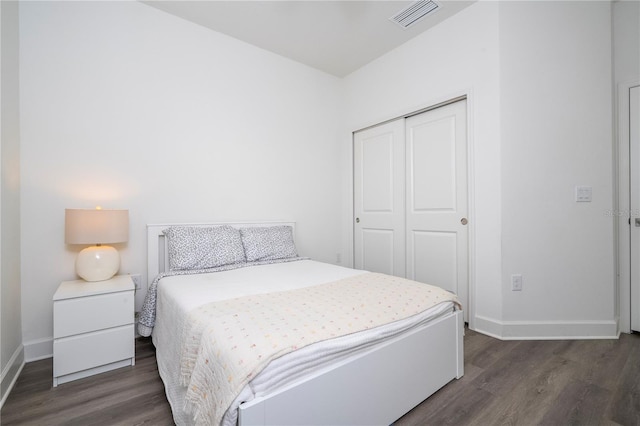 bedroom with baseboards, visible vents, dark wood-type flooring, and a closet