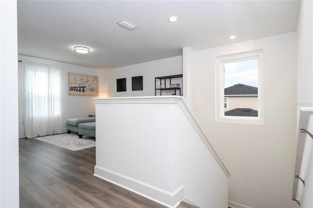 hallway with dark wood-style floors, recessed lighting, visible vents, and an upstairs landing