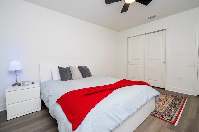 bedroom with wood finished floors, visible vents, baseboards, a ceiling fan, and a closet