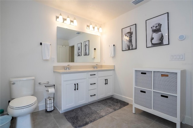 bathroom featuring toilet, double vanity, a sink, and tile patterned floors