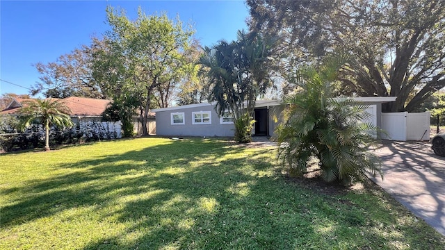 view of front of property with concrete driveway, a front yard, fence, and stucco siding