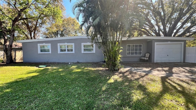 view of front facade featuring a garage, a front yard, fence, and stucco siding