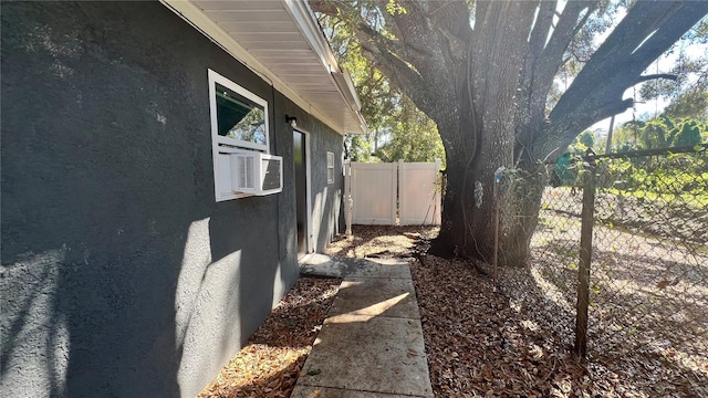 view of property exterior featuring cooling unit, fence, and stucco siding