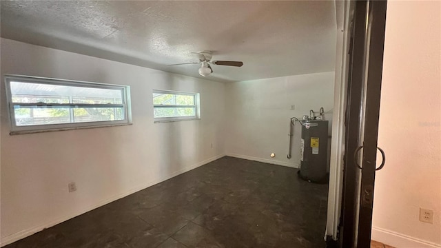 unfurnished room with ceiling fan, water heater, baseboards, and a textured ceiling