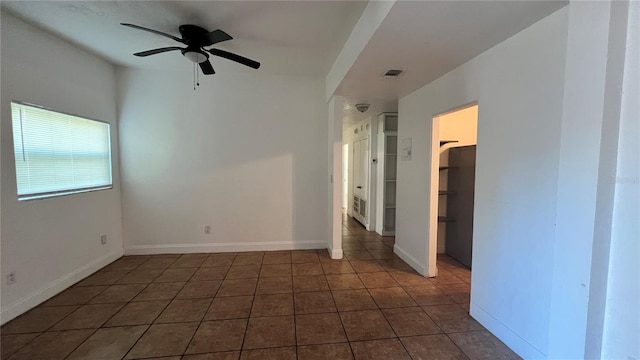 empty room featuring a ceiling fan, visible vents, baseboards, and tile patterned floors