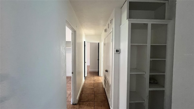 corridor featuring dark tile patterned floors and baseboards