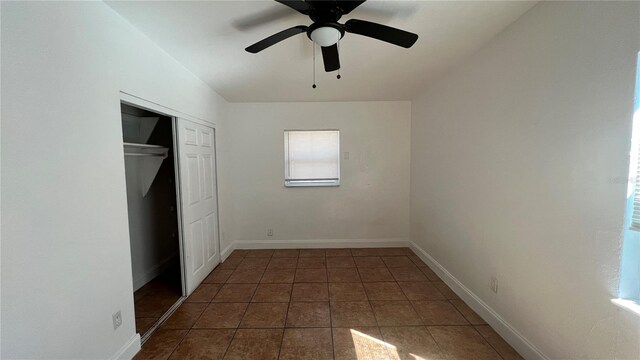 unfurnished bedroom with a closet, tile patterned flooring, a ceiling fan, and baseboards