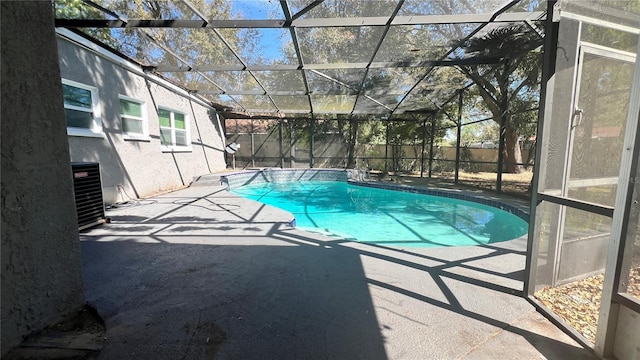 view of swimming pool featuring glass enclosure, a fenced backyard, central AC, and a patio