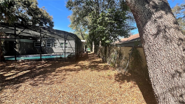 view of yard featuring an outdoor pool, a lanai, and fence