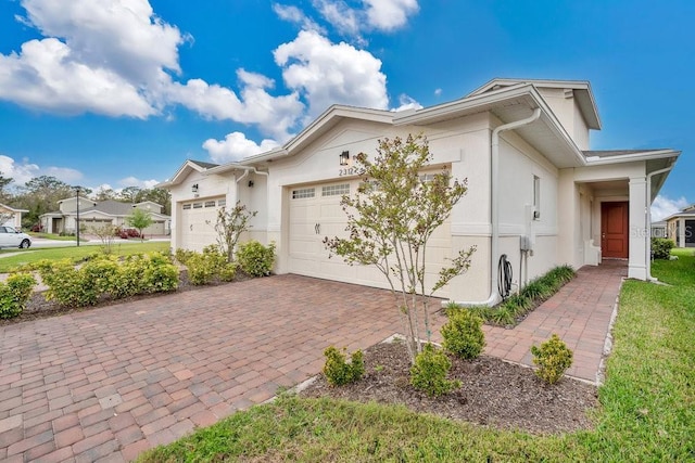 view of front of house featuring a garage, decorative driveway, and stucco siding