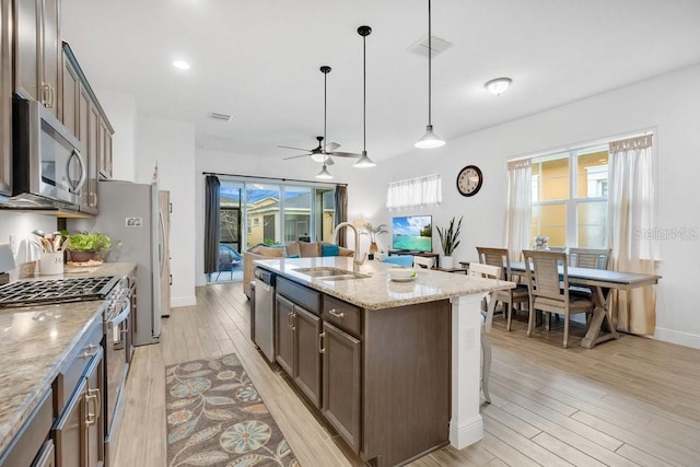 2312 Datura Loop, Saint Cloud, FL 34772 - kitchen with stainless steel appliances, a sink, light wood-style floors, light stone countertops, and decorative light fixtures
