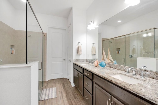2312 Datura Loop, Saint Cloud, FL 34772 - bathroom featuring double vanity, wood finished floors, a sink, and a shower stall