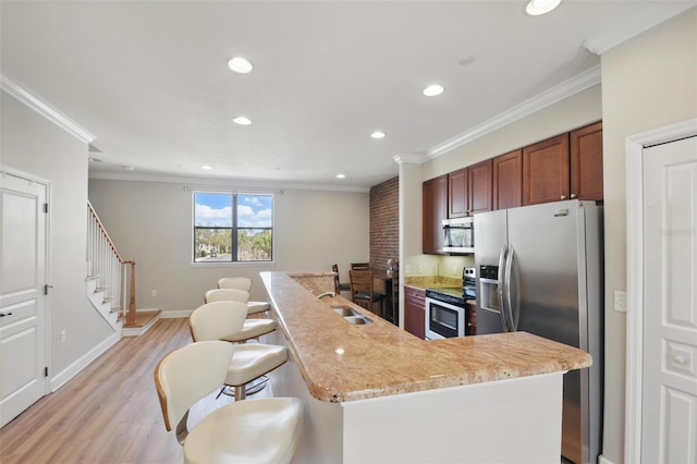 kitchen with stainless steel appliances, a sink, ornamental molding, and light wood finished floors