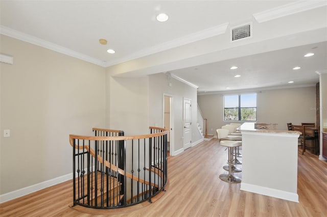 corridor featuring visible vents, light wood finished floors, an upstairs landing, and baseboards