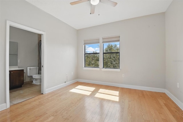 unfurnished bedroom with ceiling fan, light wood finished floors, ensuite bath, and baseboards