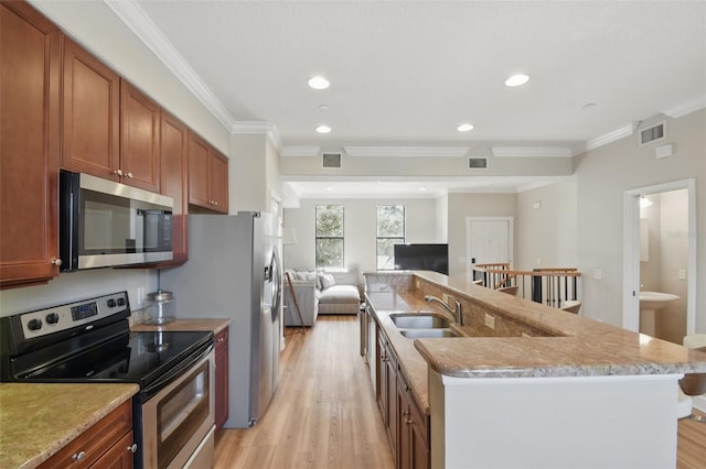 kitchen with stainless steel appliances, visible vents, a sink, and light wood finished floors