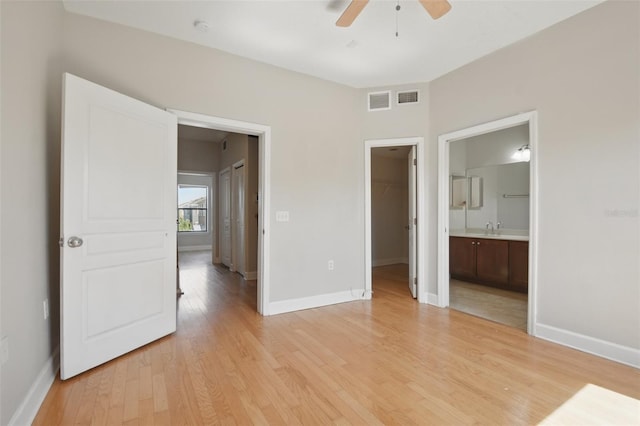 unfurnished bedroom with light wood-style floors, baseboards, a spacious closet, and visible vents