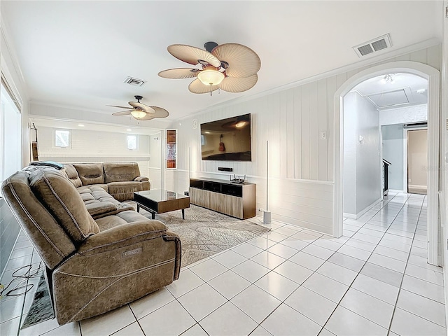 living room featuring light tile patterned floors, visible vents, arched walkways, and ornamental molding