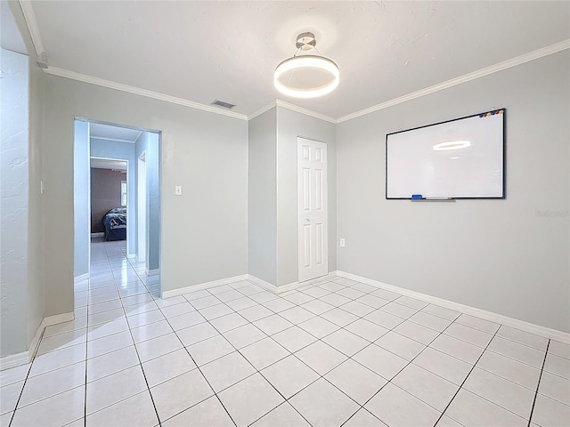 spare room featuring light tile patterned floors, visible vents, ornamental molding, and baseboards