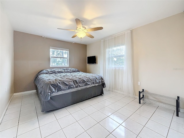 bedroom with light tile patterned floors, ceiling fan, multiple windows, and baseboards