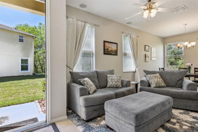 tiled living room with ceiling fan with notable chandelier and visible vents