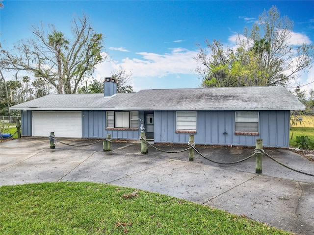 single story home featuring a chimney, a shingled roof, concrete driveway, board and batten siding, and a garage