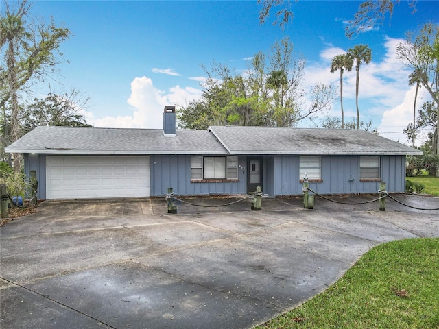 ranch-style house with a garage, a chimney, board and batten siding, and concrete driveway