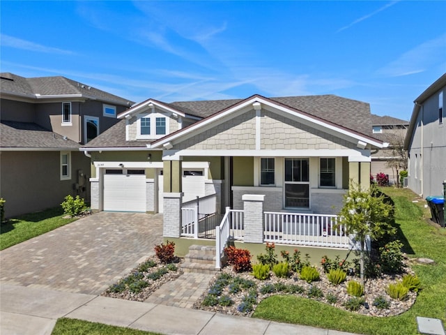 view of front of house with a garage, covered porch, decorative driveway, and roof with shingles